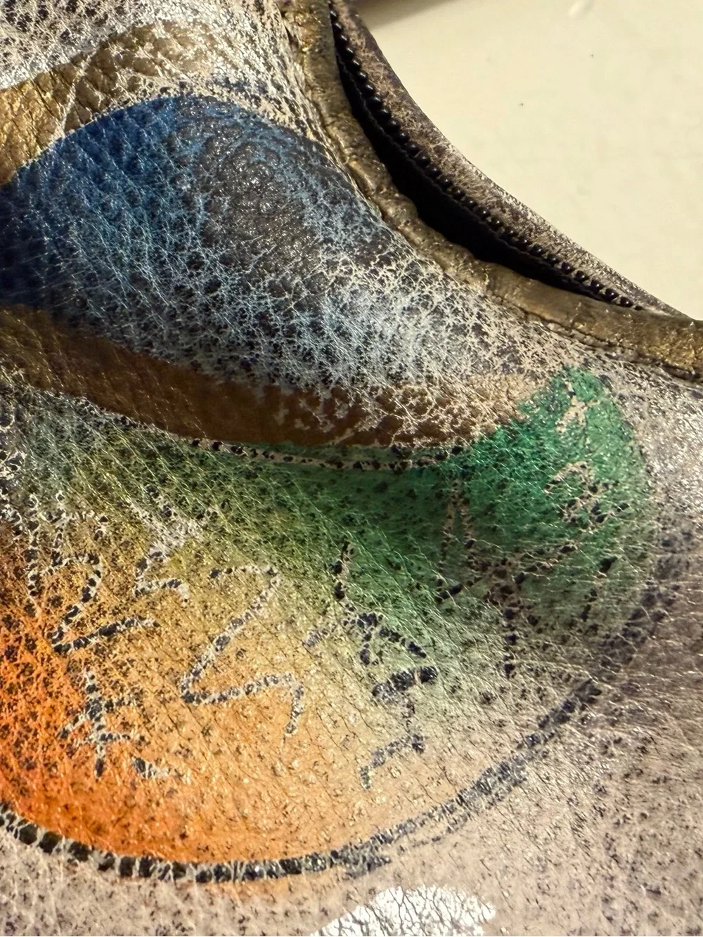 Distressed leather hobo bag with colorful abstract design on front and back.